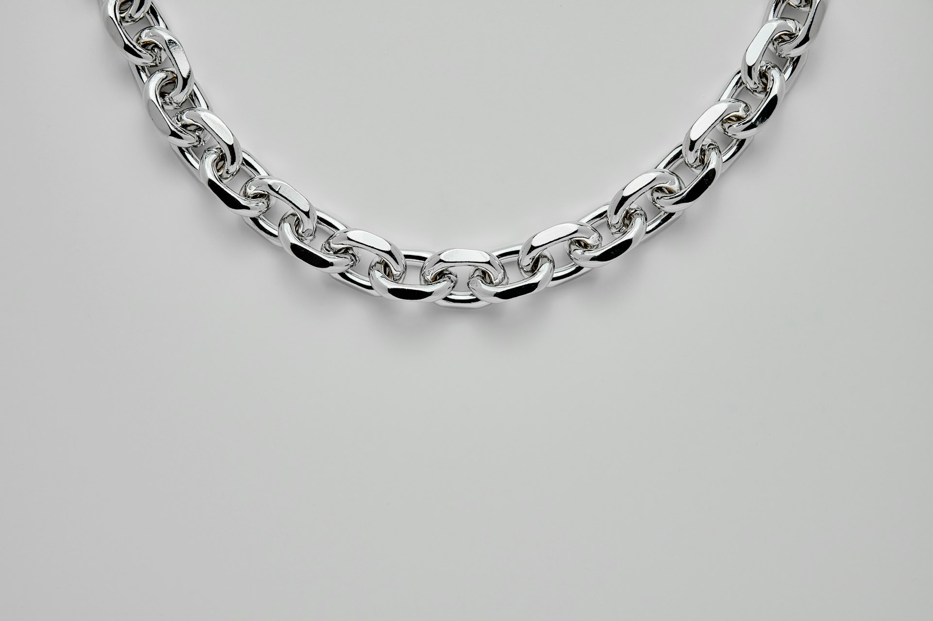 silver chain link bracelet on white surface